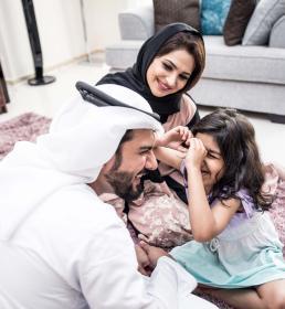 A happy Emirati family spending time together at home, symbolising the importance of financial protection and group life insurance in the UAE.