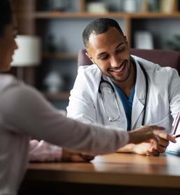 Smiling doctor meeting with a patient, reviewing medical information together — representing access to quality private healthcare through group medical insurance in the UAE.