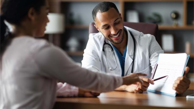 Smiling doctor meeting with a patient, reviewing medical information together — representing access to quality private healthcare through group medical insurance in the UAE.